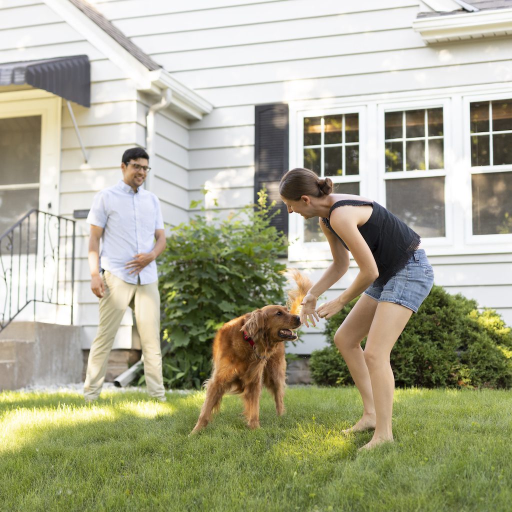 couple smiling on the lawn with dog